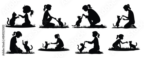 Black silhouettes of girls playing with cats on grass