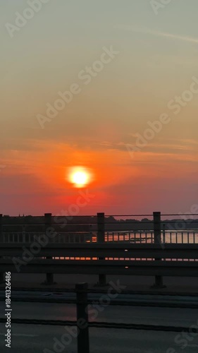 Silhouette of cyclist riding along a scenic waterfront at sunset, with vibrant colors reflecting on water, camera pans to capture the serene atmosphere and movement