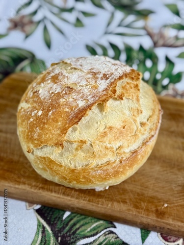 Crispy and rustic round loaf bread on a wooden board. Bread in the countryside