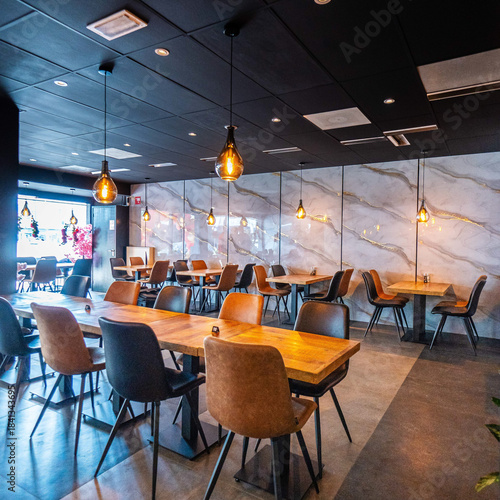 Cozy and modern coffee shop interior with wooden furniture, warm lighting, and large windows overlooking the street, creating an inviting atmosphere