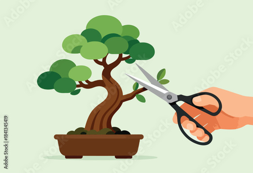 Hand holding scissors to trim a small, stylized tree in a pot