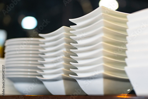 Contemporary square white plates stacked against a dark black background
