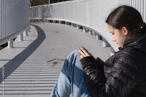 Young teen girl using smartphone feeling alone