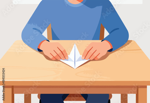Hands folding a paper boat on a wooden table