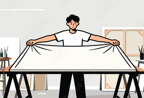 A person in a white shirt stretches a blank canvas over a table in an art studio