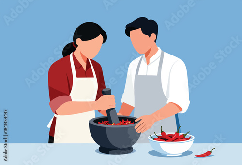 Two people in aprons prepare chilies with a mortar and pestle