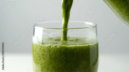 Refreshing vibrant green smoothie gracefully poured into a clear glass, highlighting a healthy, nutrient-rich beverage perfect for a revitalizing morning or a wholesome snack