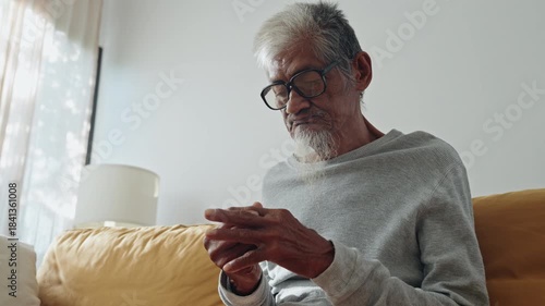 Elderly. Asian man gray hair doing muscle relaxation exercise with finger massage, stretching for aches pains at home