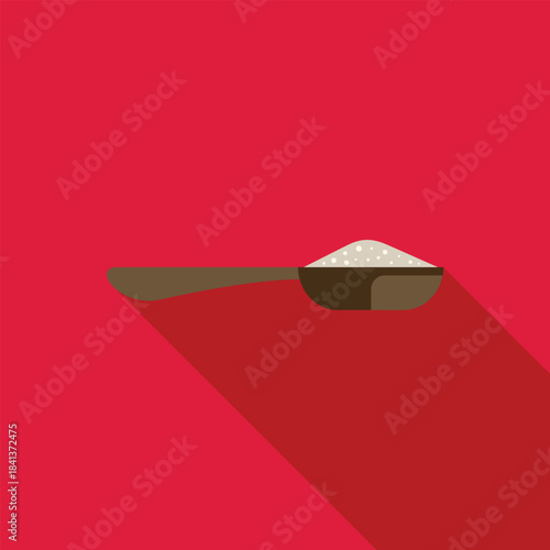 Measuring spoon holding a pile of white granular sugar on a red background