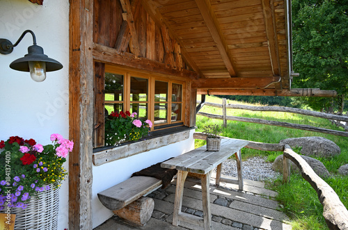 rustic alpine wooden cabin with geraniums on the window ledge in the Bavarian alpine countryside in the German Alps, Bavaria, German