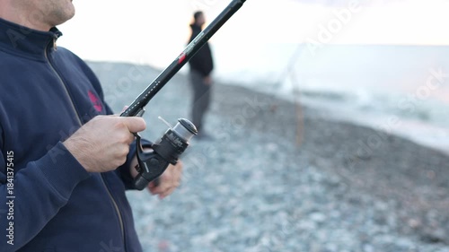 Close-up of the hands of a man who is fishing for spinning at sunset on the sea in Georgia, Batumi.
