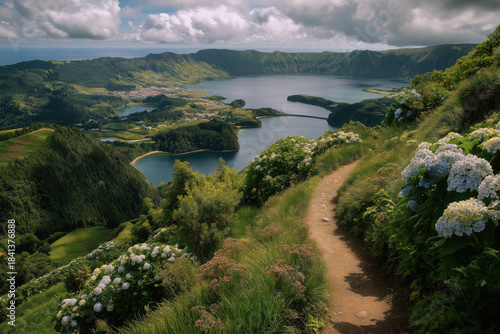 Scenic view of the Azores in Portugal with lush green hills, hydrangea-lined trail, volcanic lakes, and dramatic crater landscape under a partly cloudy sky