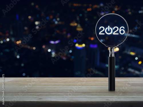 2026 start up flat icon with magnifying glass on wooden table over blur colorful night light modern city tower and skyscraper, Business happy new year 2026 success concept