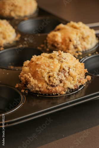 Принти на полотні Golden brown muffins close up with a crumble topping cooling down in muffin tin