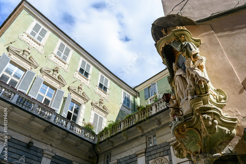 Santuario religioso católico en la esquina de un edificio histórico verde con molduras ornamentadas bajo un cielo azul nublado.