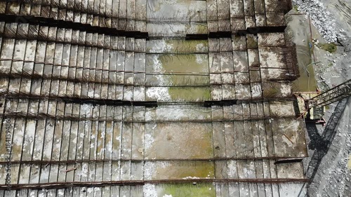 High angle drone shot looking down at the engineering details of a hydroelectric power plant project showing the iron rod mesh work prepared for the main dam structure.