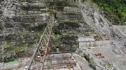 Aerial top down view of a massive grid of rusty steel rebar reinforcement laid out for a concrete foundation at a hydropower dam construction site in the mountains of Nepal