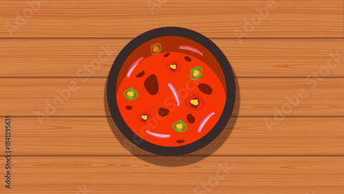 Vibrant red spicy sauce with chili and herbs in a dark bowl on a wooden table, ideal for food graphics and culinary-themed designs