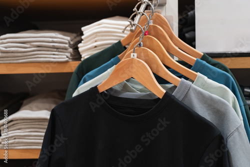 Bilde på lerret Row of colorful cotton t-shirts on wooden hangers with size tags organized on a