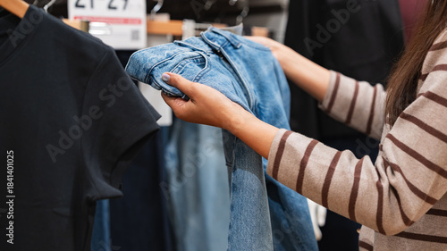 Woman comparing blue jeans in a clothing store - shopping decision and consumer behavior concept