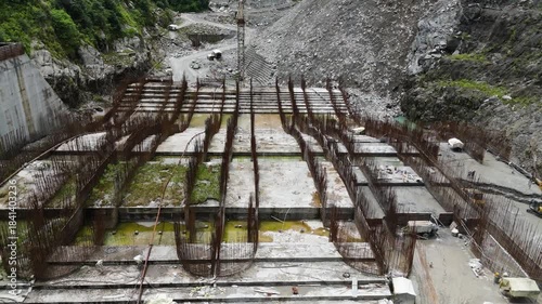 Sustainable Energy Project in Himalayas: Top Down Aerial View of Arun III Hydropower Construction with Heavy Machinery and Concrete Works on River Bank Nepal