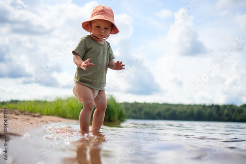 Photos A child walks on the beach with an orange hat, exploring the sandy shore and natural beauty
