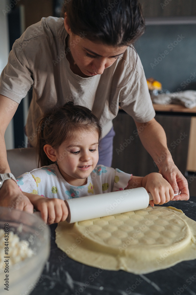Obraz premium Warm scene of mother instructing daughter in baking at kitchen table