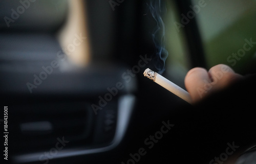 cigarette. person smoking inside a car. detail.