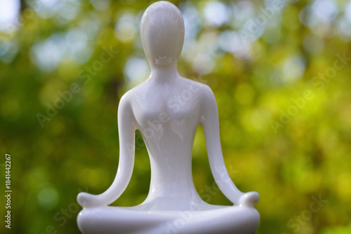 White ceramic figurine of a woman sitting in a lotus position.