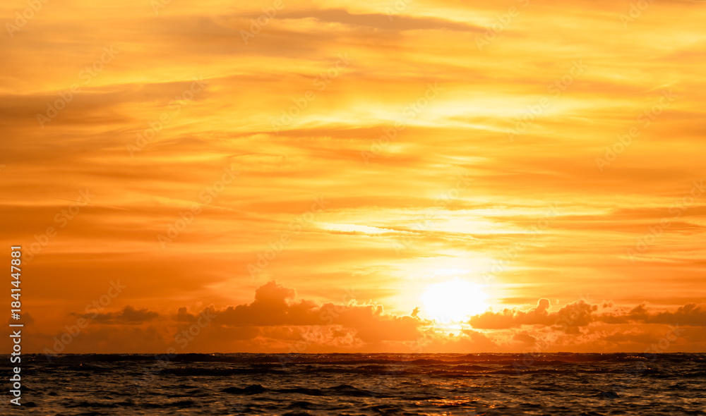 Fototapeta premium Sunset over sea water in golden hour,Yellow sunrise sky landscape with sun down with gold light on blurry background,Summer nature beach with clouds in autumn,Colorful gradient of beautiful sunlight