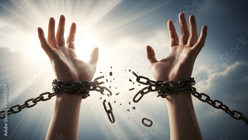 Hands breaking free from chains against a bright, dramatic sky symbolizing freedom and liberation concept