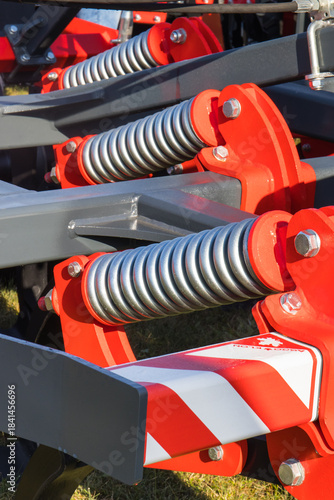Steel gray spring as part of red heavy agricultural, industrial machine. Technology