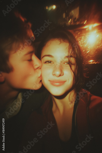 A Polaroid selfie of a young couple. The guy kisses the smiling girl on the cheek.