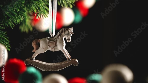 Vintage rocking horse ornament hanging from a green christmas tree branch, evoking feelings of nostalgia and childhood memories during the festive holiday season with copy space