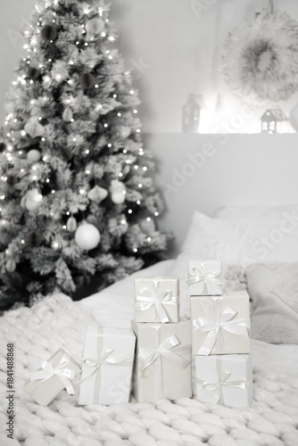 Holiday gifts arranged on a cozy knit blanket with a festive christmas tree glowing in the background, creating a serene winter scene. Color of 2026 year dancer in the white cloud