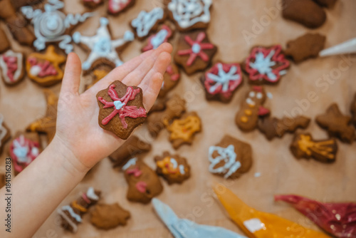 Child holds decorated cookie with other cookies spread out on table during baking activity