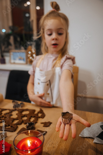 Child makes shapes with cookie cutters during baking activity at home in the evening