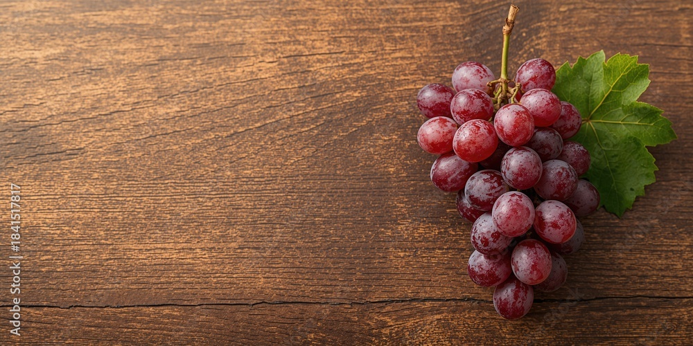 Fototapeta premium Cluster of grapes placed on rustic wood, ideal for culinary or wine-related layouts