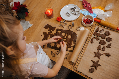 Child makes gingerbread cookies at home during the holiday season in the kitchen