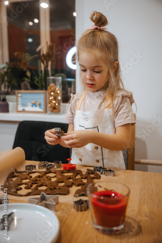 Young child makes holiday cookies in a cozy kitchen during the evening time