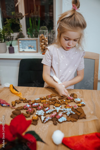 Child decorating gingerbread cookies at a table during holiday season activity