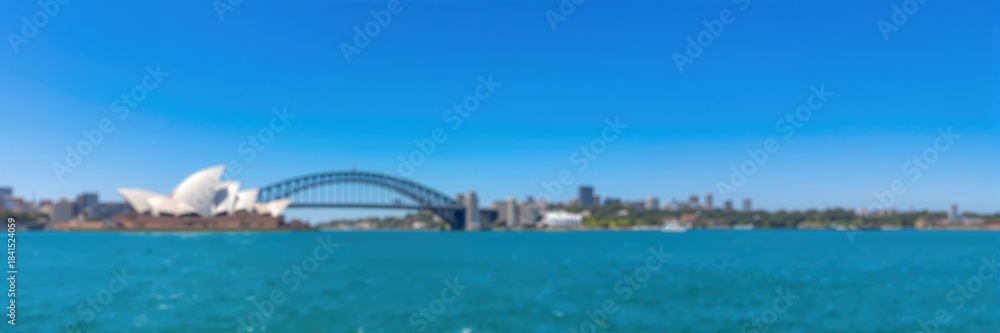 Fototapeta premium Blurred panoramic view of Opera House and Harbour Bridge on a clear sky day, suitable for graphic design backgrounds