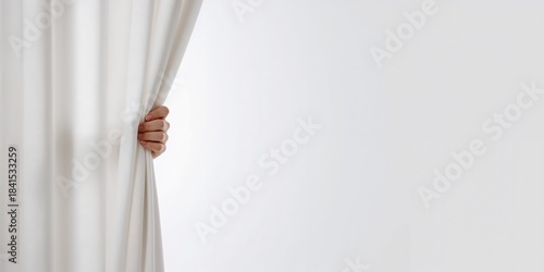 A human hand pulling open a blank curtain revealing an empty space, used as a background for text and layout