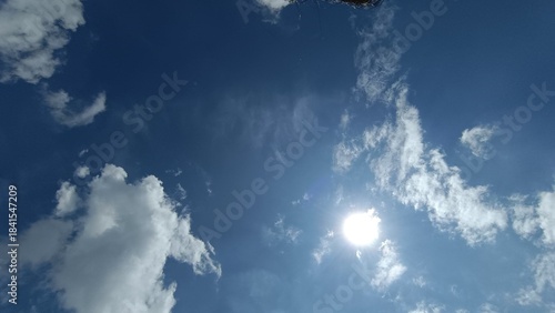 bright sun in blue sky with soft clouds