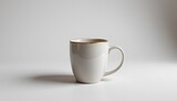 A white coffee cup sits alone on a gray surface, creating a simple yet visually appealing still life composition.
