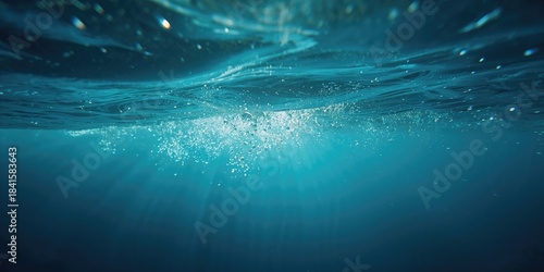 Fototapeta Naklejka Na Ścianę i Meble -  Underwater view of blue ocean waves with bubbles, highlighting water transparency and wave dynamics
