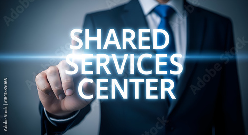 Businessman in suit and tie pointing to shared services center text with glowing blue lines, representing business and corporate concepts