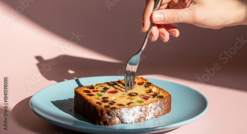 Hand Holding Fork Ready to Slice Delicious Fruit Cake on Plate