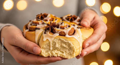 Freshly Baked Cinnamon Rolls with Icing and Spices in Hand