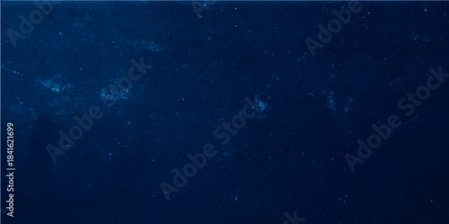 Dark blue grunge texture background with abstract light rays suggesting night sky galaxy stars or deep sea water motion